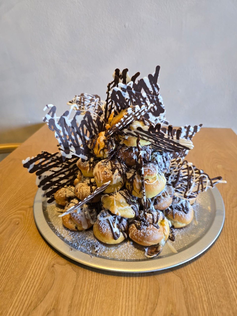 Torre de profiteroles con decoración de chocolate, servicio de catering